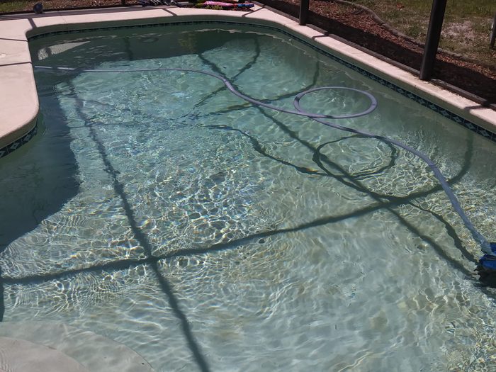 Vacuum hose working across the floor of a screened Melbourne pool during a weekly visit